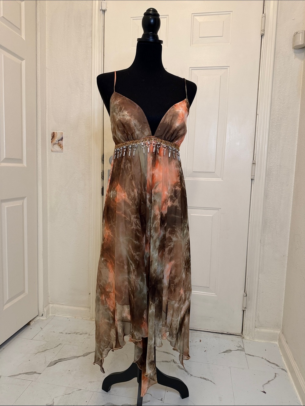 This ABS dress features a handkerchief hem beaded waist vibrant abstract colors